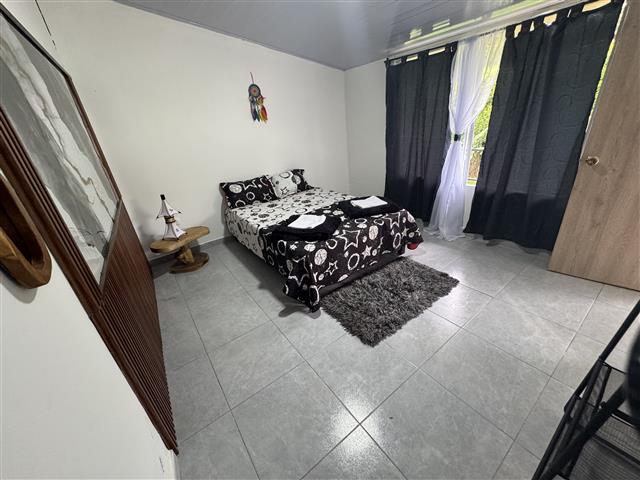eco-hotel-gaia-11 - Hoteles en el Quindío Eje Cafetero, Alojamientos, Alquiler de fincas Small bedroom with a double bed in black-and-white patterned bedding, a gray shag rug, and dark curtains by a window.