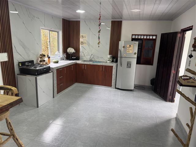 eco-hotel-gaia-14 - Hoteles en el Quindío Eje Cafetero, Alojamientos, Alquiler de fincas L-shaped kitchen with dark wood cabinets, gray countertops, sink, stove, and a silver refrigerator on the right.